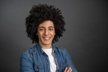 Waist up of a curly-haired young man on grey background