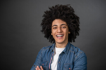 Fototapeta na wymiar Waist up of a curly-haired young man on grey background