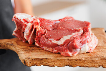 Butcher woman prepare fresh meat pork entrecote steak on wooden board, top view on dark background