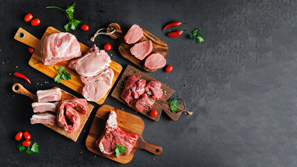 Variety of raw beef meat and pork ribs, pig steaks for grilling with seasoning on wooden board,...