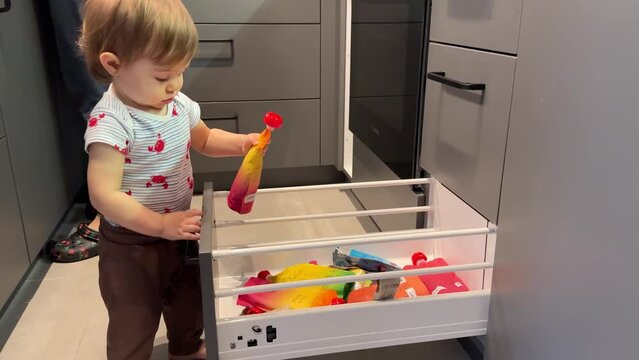 One year old child looking trough the kitchen drawer