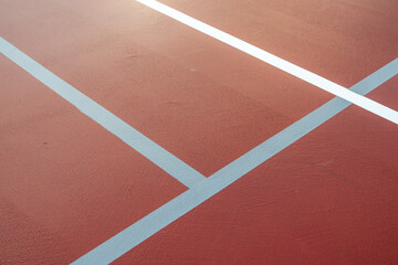 Wet red tennis court with white lines combined with gray pickleball lines