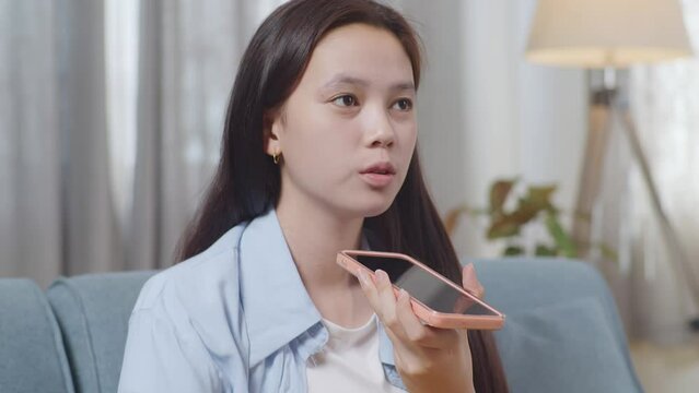 Close Up Of Asian Teen Girl Talking On Smartphone While Sitting On Sofa In The Living Room At Home
