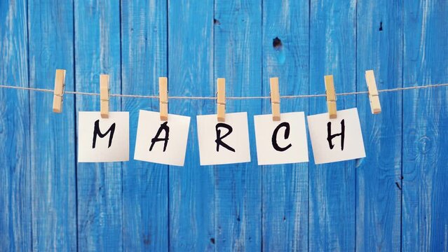 March word. March month. The inscription on the cards on a wooden blue background. Spring, warming. Spring days and warm sun. Concept of letters and text or phrase.