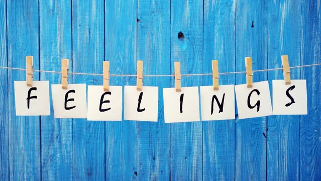 The word is feelings. The inscription on sheets of paper on a blue background. People's feelings.