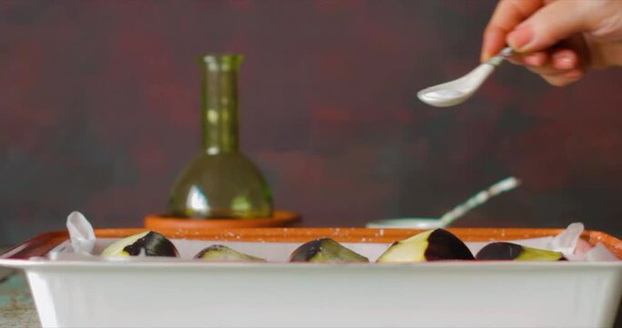 making an eggplant dish, salt, pepper and oil are added to the peeled eggplants
