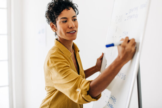 Black business woman writing on a white board in an office