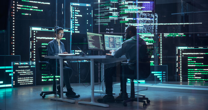 Portrait Two Diverse Developpers Working on Computers, Typing Lines of Code that Appear on Big Screens Surrounding Them. Male and Female Programmers Creating Innovative Software Together, Fixing Bugs