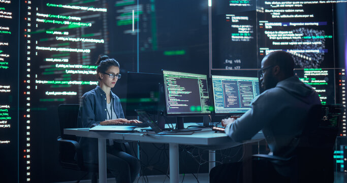 Portrait of Two Programmers Working in a Monitoring Control Room, Surrounded by Big Screens Displaying Lines of Programming Language Code. Portrait of Diverse Developers Creating a Software, Coding - Powered by Adobe