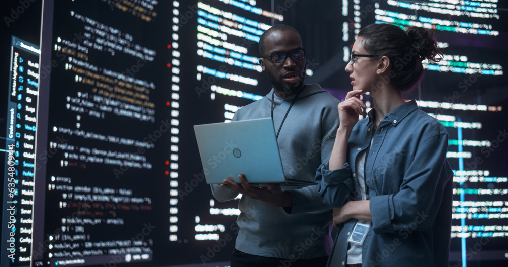 Aufkleber Portrait of Two Diverse Developers Using Laptop Computer, Discussing Lines of Code that Appear on Big Screens Surrounding Them. Male and Female Programmers Creating a Software Together and Fixing Bugs
