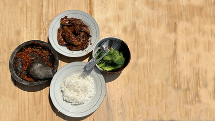 a grilled chicken dish with rice, sambal and vegetables.