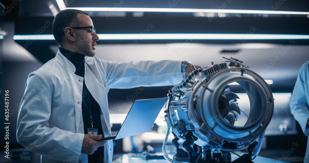 Leinwandbilder Young Group of Engineers Collaborate on a New Type of a Gas Turbine Engine. Male Project Leader Holding a Laptop Computer and Explaining the Innovative Technology in Scientific Technology Lab