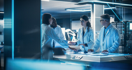 Diverse Team of Industrial Robotics Specialists Gathered Around a Table With Development Parts of a...