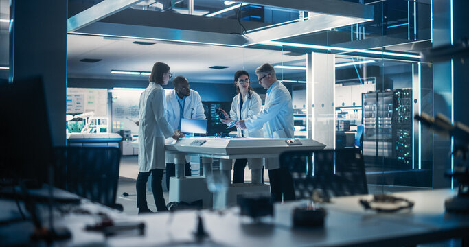 Team of Industrial Engineers Working on a Bionic Robot Arm at a Startup Factory. Multiethnic Male and Female Scientists Having a Conversation About an Electronic Component for a Humanoid AI Robot - Powered by Adobe