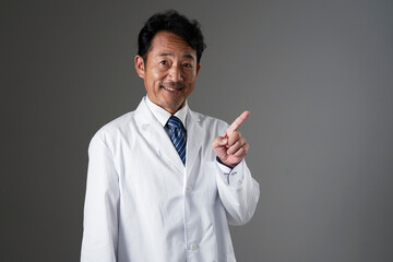 右側を指差すミドルエイジの医者　黒背景