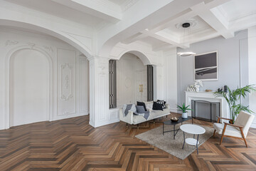 a chic expensive bright interior of a huge living room in a historic mansion with arched arches, columns and white walls decorated with ornaments and stucco.