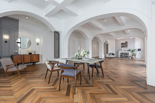 a view of a set dining table in a chic expensive bright interior of a huge living room in a historic mansion with arched arches, columns and white walls decorated with ornaments and stucco.