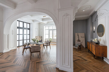 a chic expensive bright interior of a huge living room in a historic mansion with arched arches, columns and white walls decorated with ornaments and stucco.