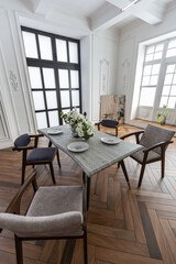 a view of a set dining table in a chic expensive bright interior of a huge living room in a historic mansion with arched arches, columns and white walls decorated with ornaments and stucco.
