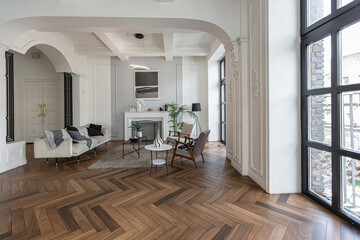 a chic expensive bright interior of a huge living room in a historic mansion with arched arches, columns and white walls decorated with ornaments and stucco.