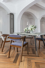 a view of a set dining table in a chic expensive bright interior of a huge living room in a historic mansion with arched arches, columns and white walls decorated with ornaments and stucco.