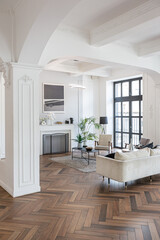 a chic expensive bright interior of a huge living room in a historic mansion with arched arches, columns and white walls decorated with ornaments and stucco.