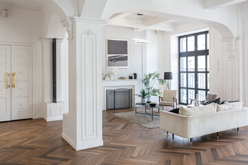 a chic expensive bright interior of a huge living room in a historic mansion with arched arches, columns and white walls decorated with ornaments and stucco.