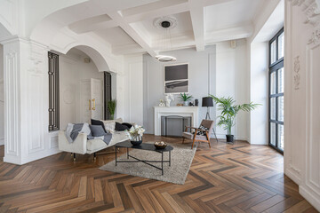 a chic expensive bright interior of a huge living room in a historic mansion with arched arches, columns and white walls decorated with ornaments and stucco.