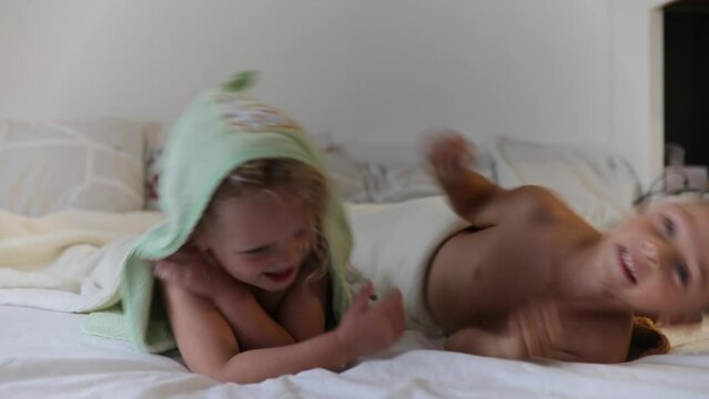 Two cute blond beautiful children, boy and girl, lying on the bed after bath, cuddling together