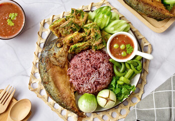 Thai spicy shrimp paste dipping sauce ( Nam prik kapi )with cooked riceberry rice and fried mackerel fish and fried egg with climbing wattle and vegetable set.