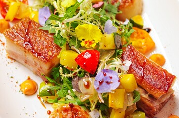 Cantonese crispy roast pork Siu Yuk and seared scallops with corn and asparagus salad as garnish on white plate