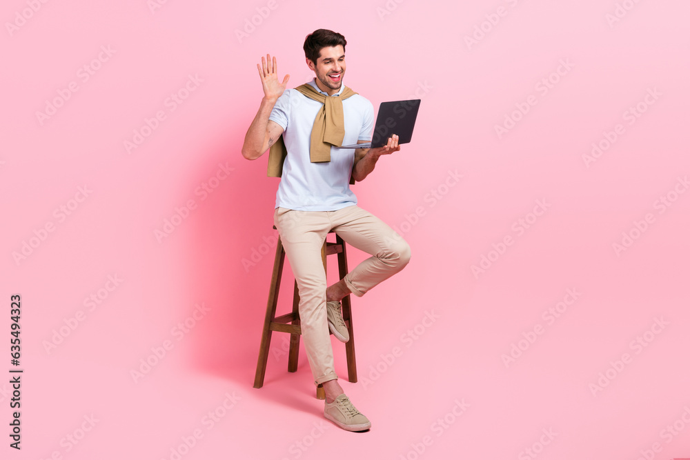 Poster full body portrait of positive friendly guy sit stool arm palm waving communicate video call netbook