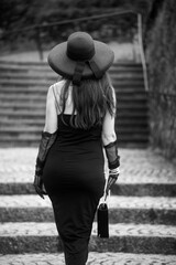 Portrait on unrecognized woman wearing a black dress walking in the street - 635495157