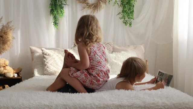 Cute sweet toddler children, tickling feet on the bed, laughing and smiling, childish mischief, happiness