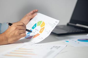 The astute business analyst is meticulously dissecting revenue graphs on the workstation, while...
