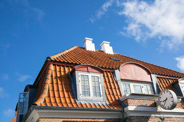 Tiled house roof with chimney and windows.