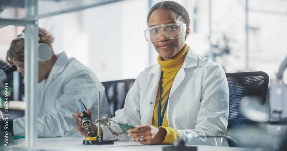 Poster Diverse Team of Multiethnic Young Scientists Passing Internship in a Modern High Tech Laboratory. Cute African Female Looking at Camera and Smiling while Working with Soldering Iron
