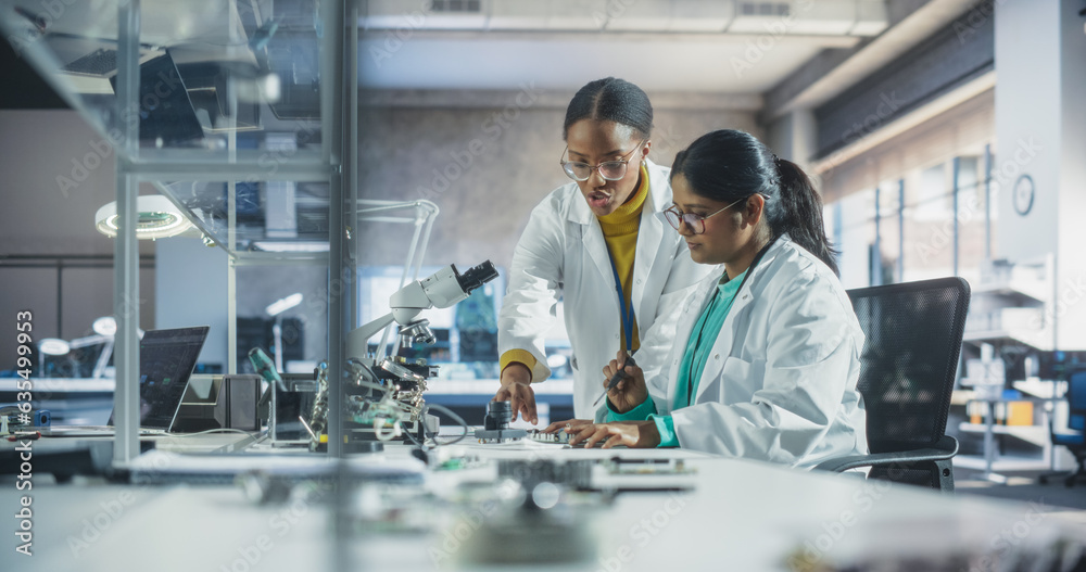 Poster Indian Girl Having a Conversation with a Mentor in a Laboratory, While Working on a Circuit Board for a Project. Young Scholar Talking with a Scientist About Changing the CPU Memory Characteristics