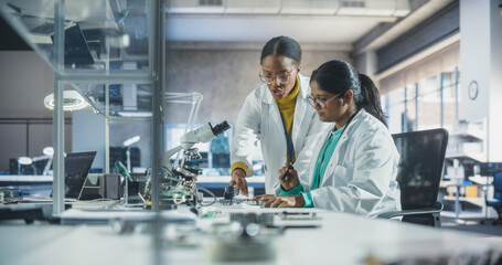 Indian Girl Having a Conversation with a Mentor in a Laboratory, While Working on a Circuit Board...