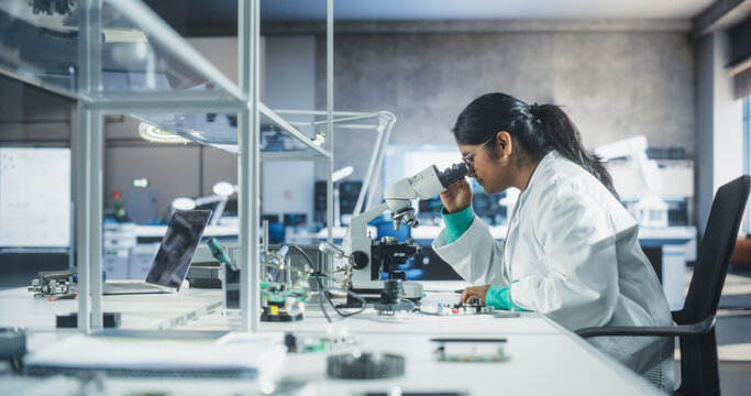 College Science Classroom: Diverse Young South Asian Female Experimenting with Computer Components, Soldering Circuit Boards, Using Microscope and a Screwdriver in a Laboratory