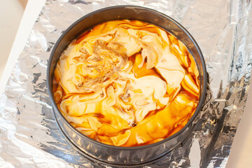 Cheesecake with salted caramel before preparation. Metal baking pan over the foil to make a water bath inside the oven