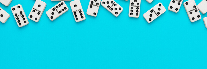 Domino pieces on turquoise blue background with copy space. Flat lay minimalist photo of some domino bones.