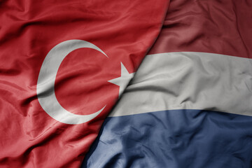 big waving national colorful flag of turkey and national flag of netherlands .