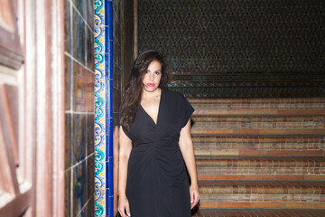 Young beautiful woman with long brown hair walking down the stairs of a monument in seville, the...