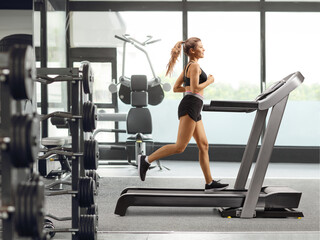 Obraz na płótnie Canvas Young female running on a treadmill at a gym