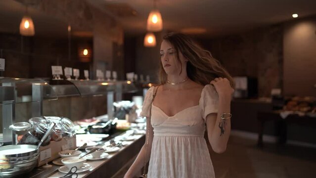 Chica joven en cafeter&iacute;a restaurante de hotel de lujo tomando bebida caliente mirando por la ventana y visitando el establecimiento