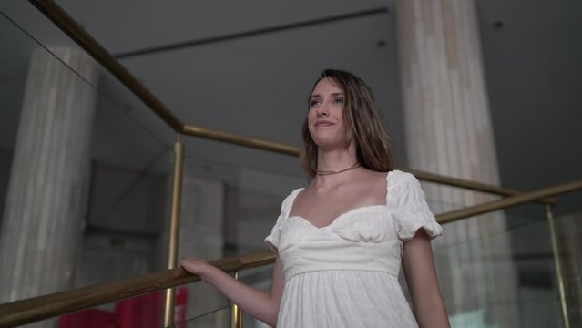 Plano medio de chica joven bajando escaleras caracol de un hotel de lujo