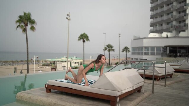 Chica joven en hamaca de piscina de hotel leyendo y disfrutando de las vacaciones