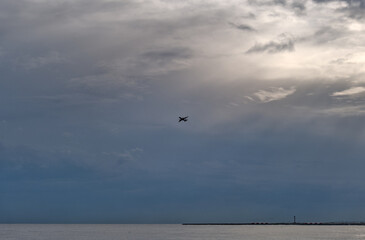 Plane taking-off above sea in Nice, France with sun beams in background