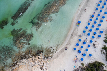 Fototapeta na wymiar Drone aerial of tropical sandy beach holiday resort with beach umbrellas and people swimming and relaxing. Summer vacations.